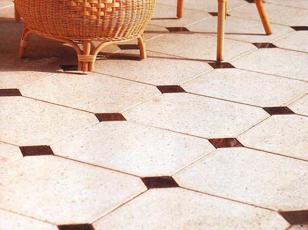Concrete tiles with decorative inlays in a patio setting, showing a smooth surface finish.
